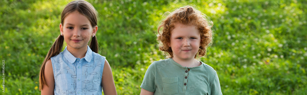 smiling girl and boy looking at camera while standing outdoors, banner. smiling girl and boy looking at camera while standing outdoors, banner.