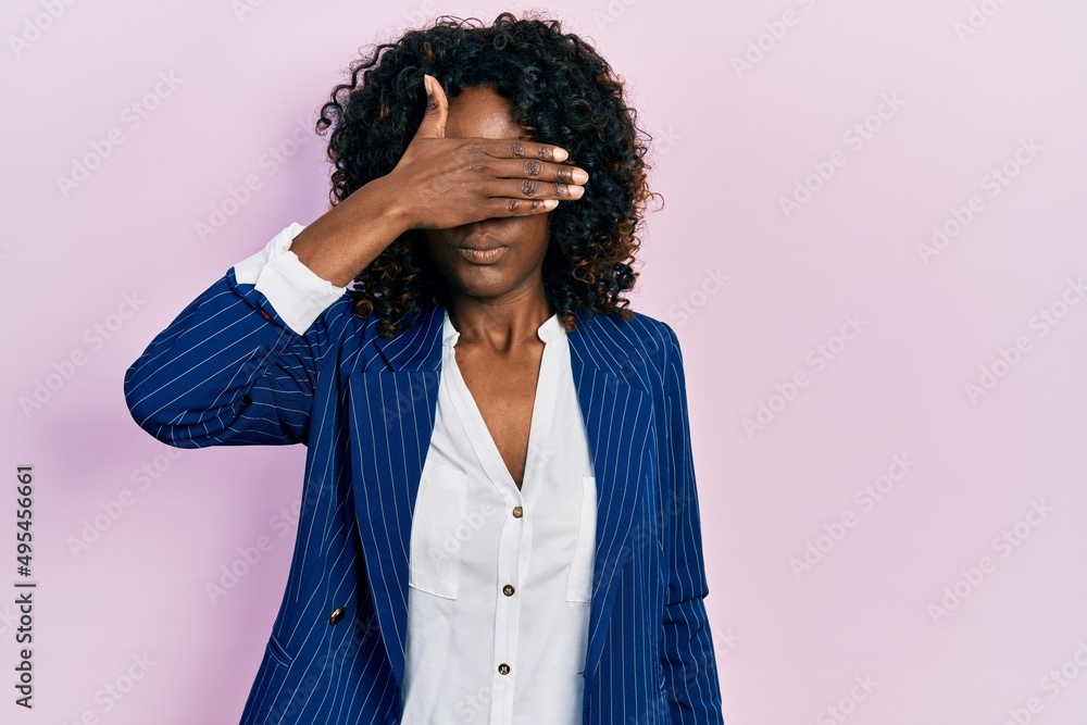 Young african american woman wearing business clothes and glasses covering eyes with hand, looking serious and sad. sightless, hiding and rejection concept Young african american woman wearing business clothes and glasses covering eyes with hand, looking serious and sad. sightless, hiding and rejection concept