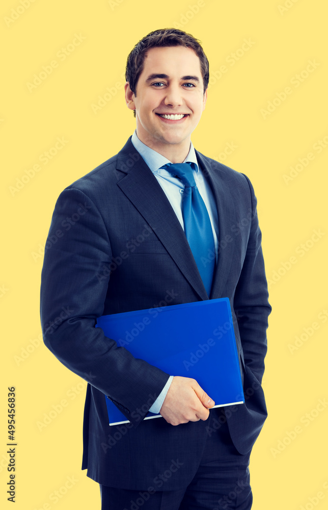 Portrait of smiling middle aged confident businessman, isolated over yellow color background. Happy business man with blue folder at studio. Portrait of smiling middle aged confident businessman, isolated over yellow color background. Happy business man with blue folder at studio.