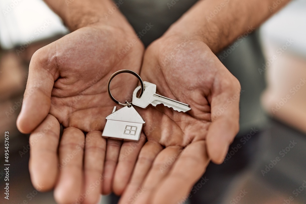 Young hispanic man holding key of new house at home Young hispanic man holding key of new house at home