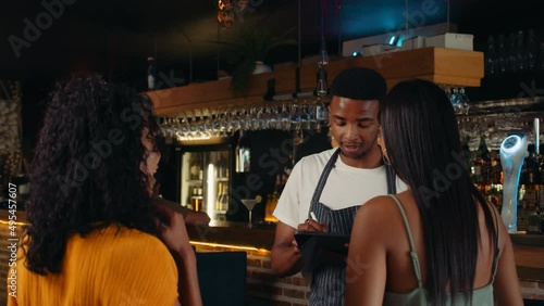 African American waiter greeting female customers at the door