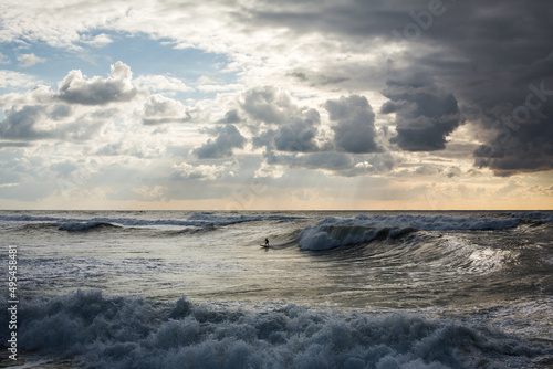 Surfers ride the sea waves at sunset