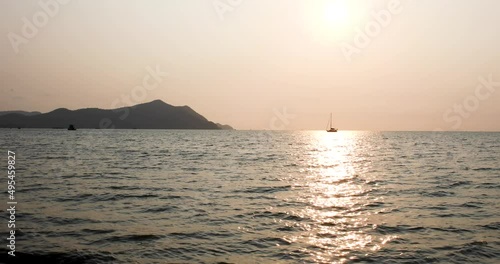 Scenic View of a Sunset with a Yacht on the Horizon During a Beautiful Sunset in Bangsaray near Pattaya, Thailand. Wide Shot in 4K. photo