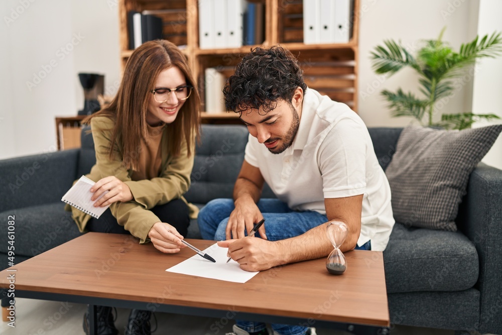 Man and woman having psychology session writing on paperwork at psychology center Man and woman having psychology session writing on paperwork at psychology center