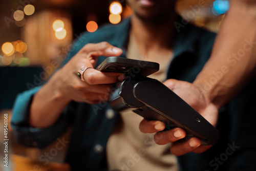 close up of customer paying with cellular device and card machine