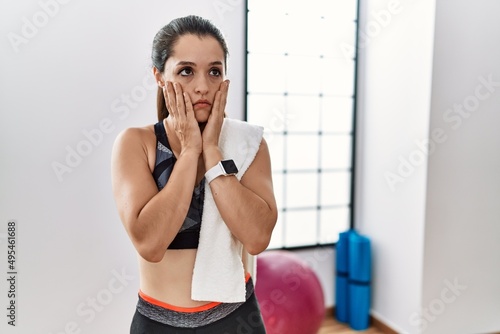Young brunette woman wearing sportswear and towel at the gym tired hands covering face, depression and sadness, upset and irritated for problem