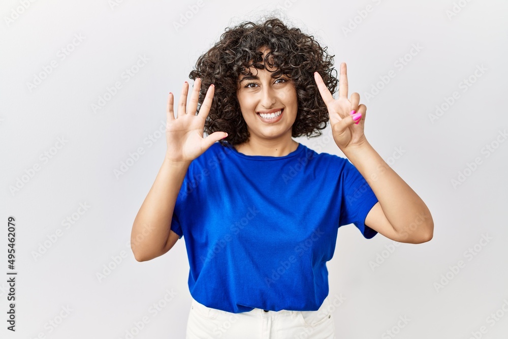 Young middle eastern woman standing over isolated background showing and pointing up with fingers number seven while smiling confident and happy. Young middle eastern woman standing over isolated background showing and pointing up with fingers number seven while smiling confident and happy.