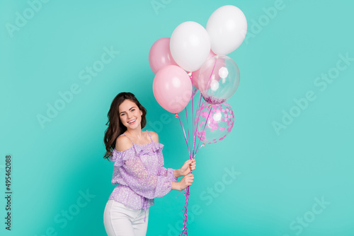 Portrait of gorgeous friendly person hold balloons toothy smile isolated on turquoise color background