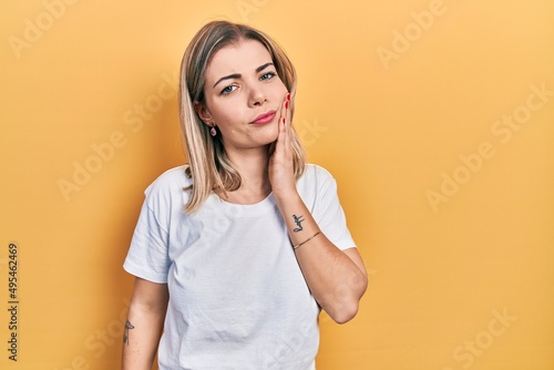 Beautiful caucasian woman wearing casual white t shirt touching mouth with hand with painful expression because of toothache or dental illness on teeth. dentist