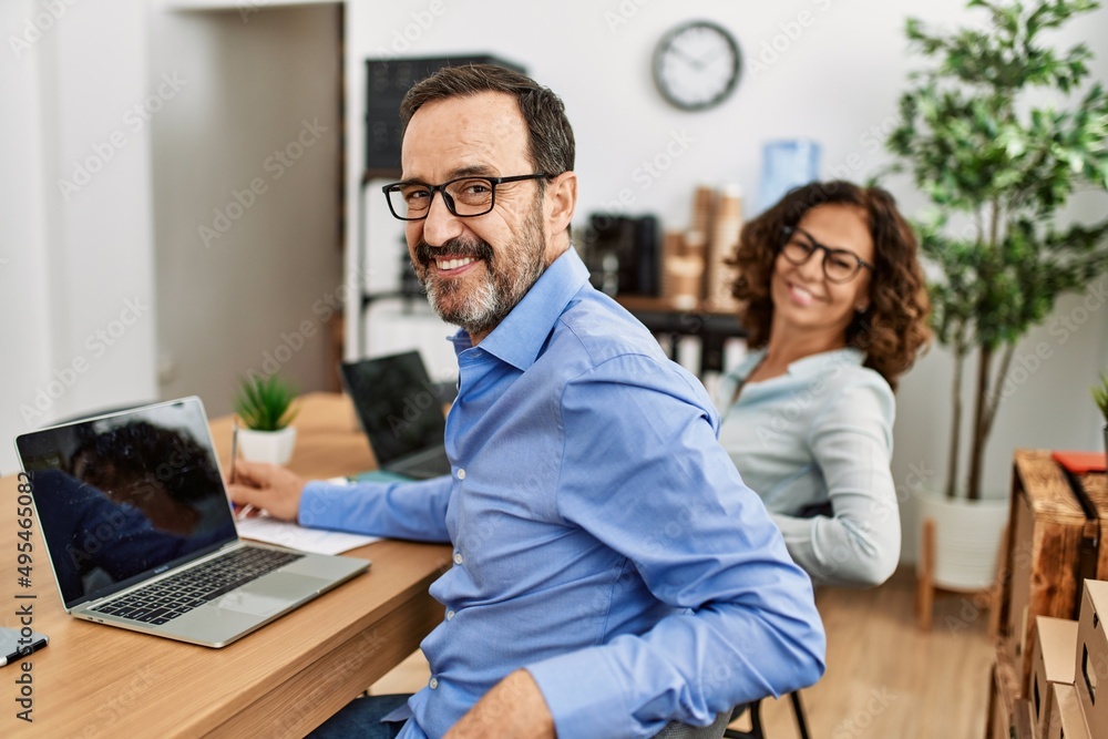 Two middle age business workers smiling happy working at the office. Two middle age business workers smiling happy working at the office.