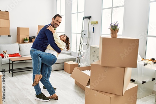 Middle age hispanic couple smiling happy and dancing at new home.