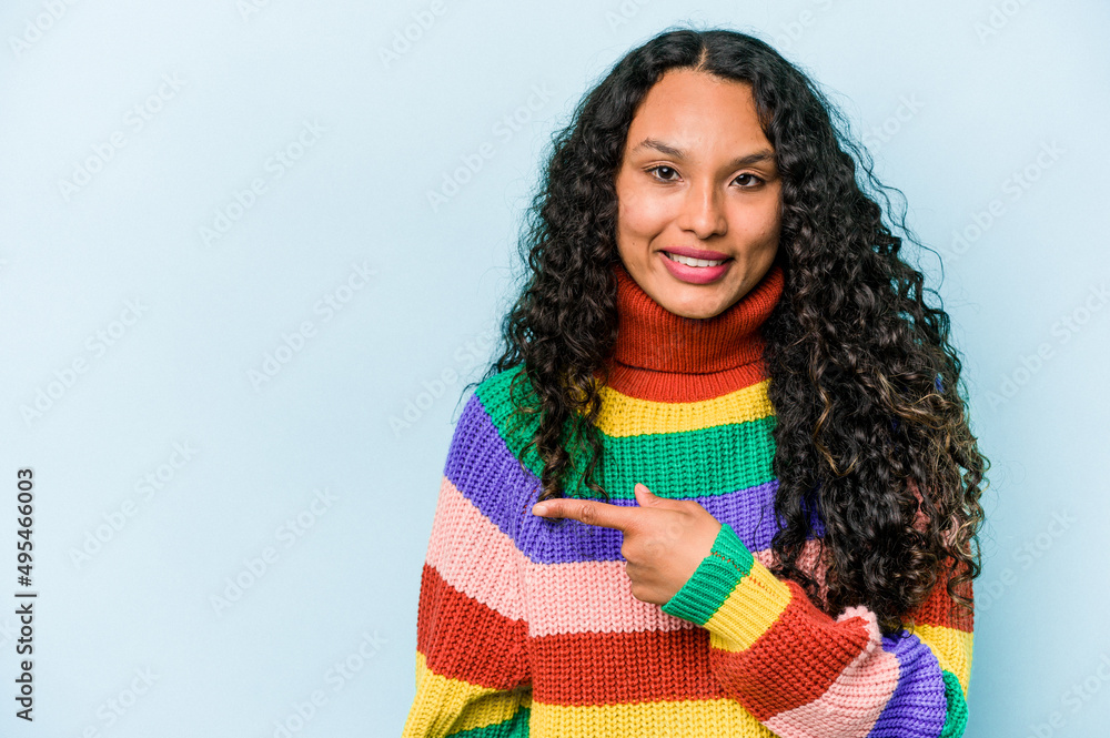 Young hispanic woman isolated on blue background smiling and pointing aside, showing something at blank space. Young hispanic woman isolated on blue background smiling and pointing aside, showing something at blank space.
