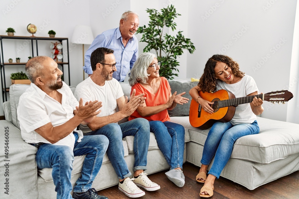 Obraz premium Group of middle age friends having party playing classical guitar sitting on the sofa at home.