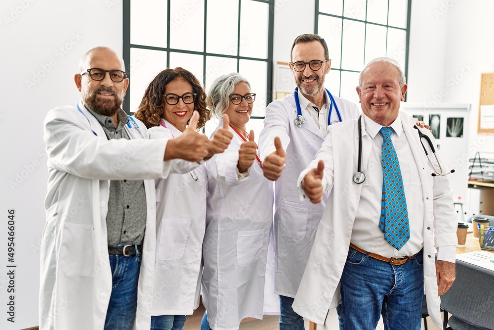 Group of middle age doctor smiling happy doing ok sign with thumbs up in a medical meeting at the clinic office. Group of middle age doctor smiling happy doing ok sign with thumbs up in a medical meeting at the clinic office.
