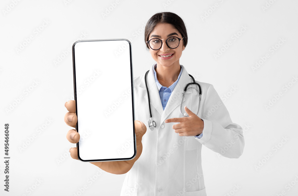 Indian female physician in uniform holding smartphone with empty screen