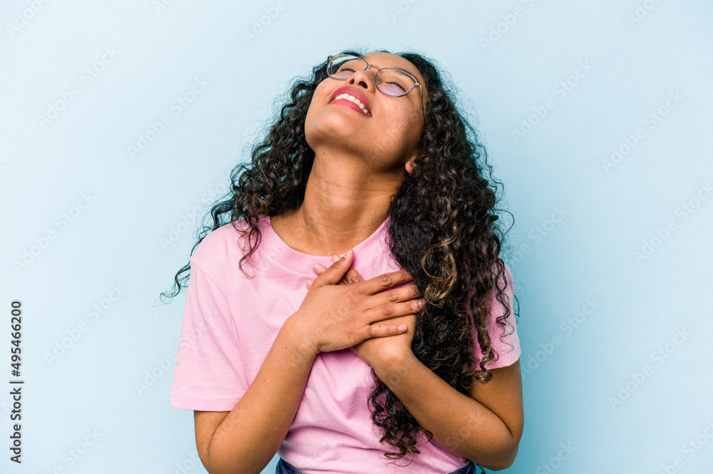 Young hispanic woman isolated on blue background has friendly expression, pressing palm to chest. Love concept. Young hispanic woman isolated on blue background has friendly expression, pressing palm to chest. Love concept.