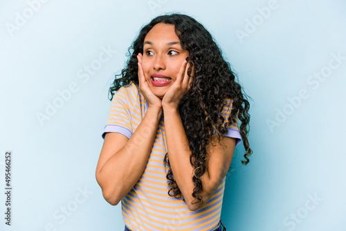 Young hispanic woman isolated on blue background scared and afraid. © Asier