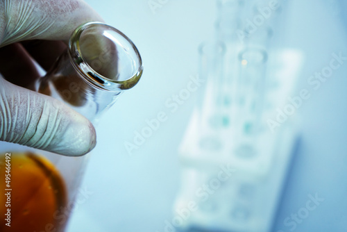 Close up view of transparent glass test flask with brown liquid inside. Isolated on background. Laboratory tests and research. Chemistry science or medical biology experiment. Laboratory background.