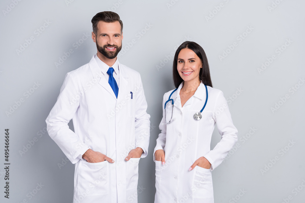 Portrait of two confident positive people hands pockets look camera isolated on grey color background Portrait of two confident positive people hands pockets look camera isolated on grey color background