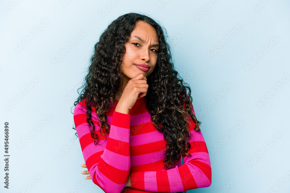 Young hispanic woman isolated on blue background thinking and looking up, being reflective, contemplating, having a fantasy. Young hispanic woman isolated on blue background thinking and looking up, being reflective, contemplating, having a fantasy.