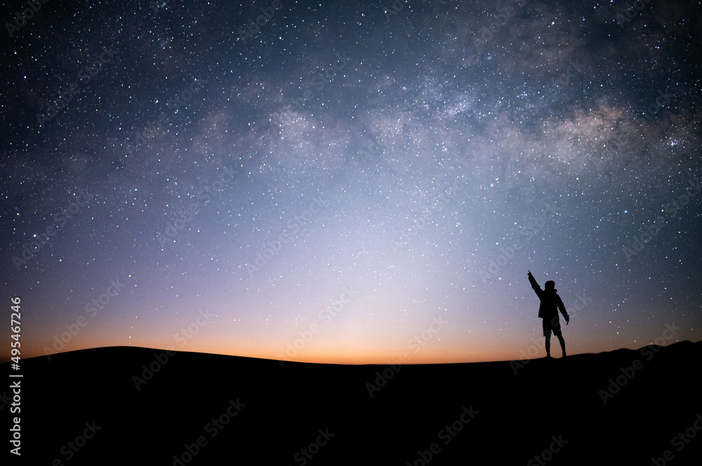 Young traveler with backpack standing and open arms and watched night sky view, star and milky way alone on top of the mountain. He enjoyed traveling and was successful when he reached the summit.