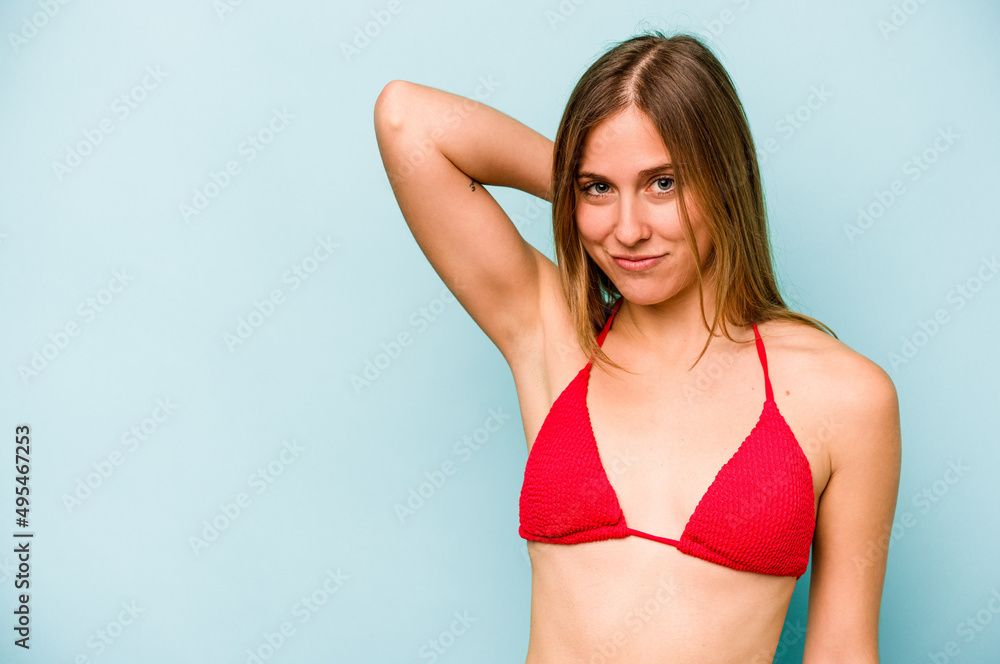 Young caucasian woman going to the beach isolated on blue background touching back of head, thinking and making a choice. Young caucasian woman going to the beach isolated on blue background touching back of head, thinking and making a choice.