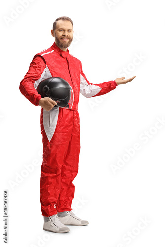 Full length shot of a car racer holding a helmet and showing with hand