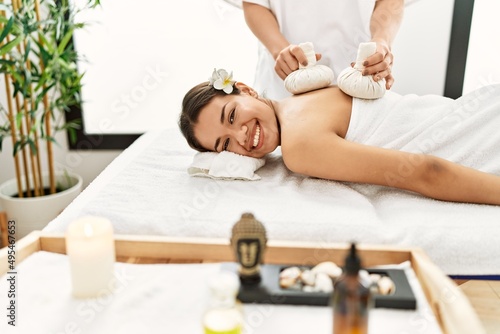 Young latin woman relaxed having back massage with thai bags at beauty center