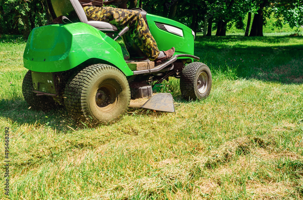 Obraz premium Mowing grass in the park. Lawn mower. Lawn care.