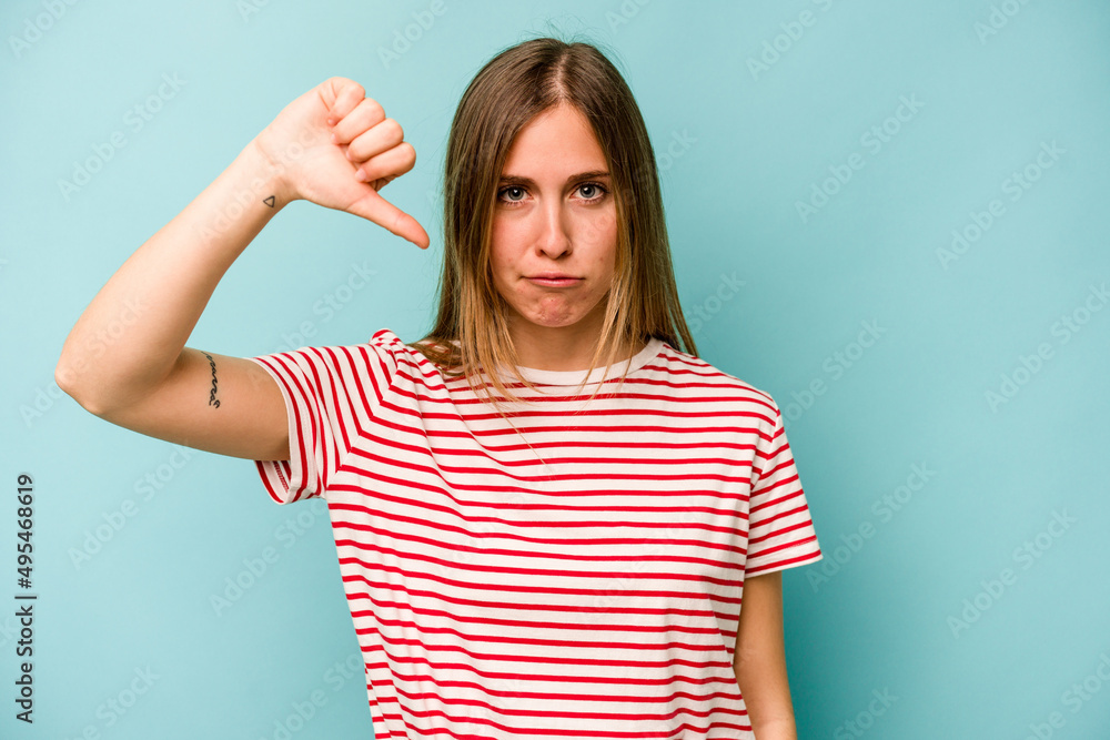 Young caucasian woman isolated on blue background showing thumb down and expressing dislike. Young caucasian woman isolated on blue background showing thumb down and expressing dislike.