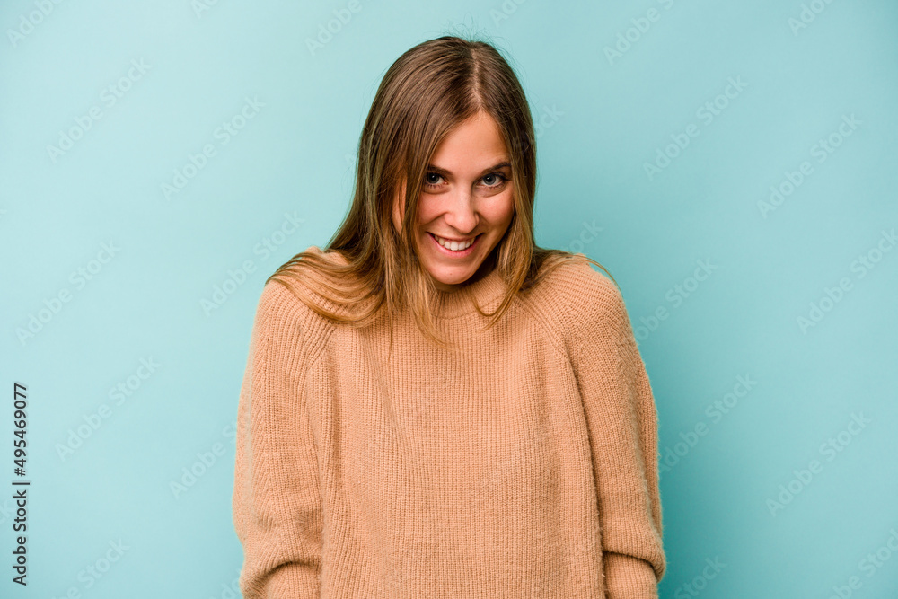 Fototapeta premium Young caucasian woman isolated on blue background laughs and closes eyes, feels relaxed and happy.