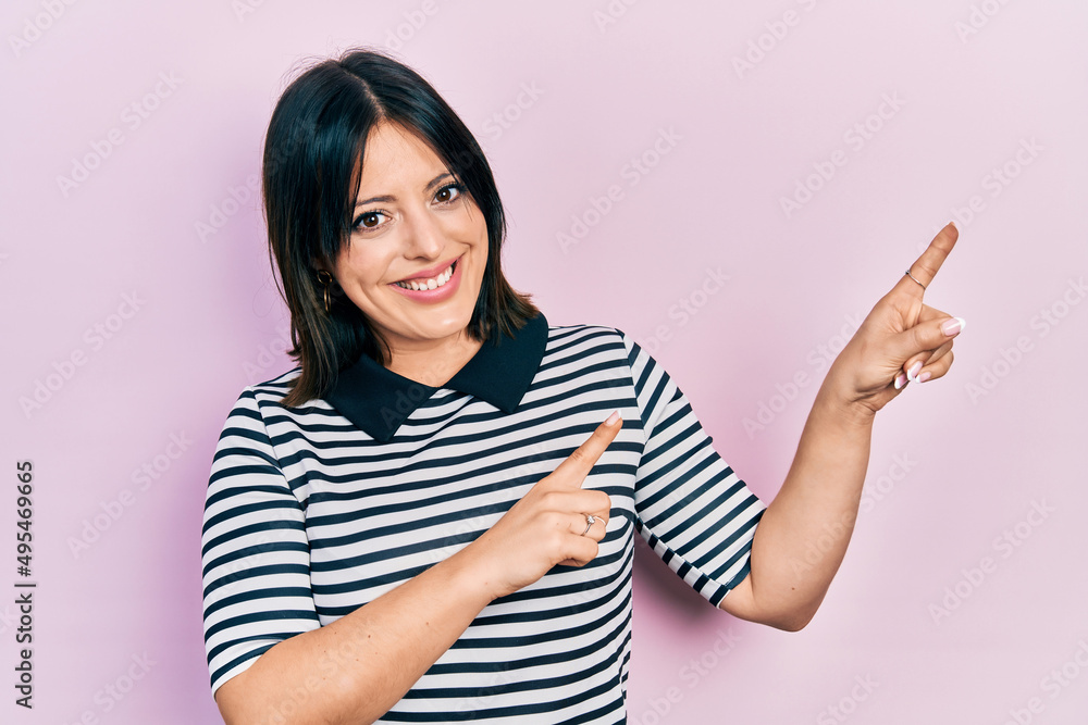 Young hispanic woman wearing casual clothes smiling and looking at the camera pointing with two hands and fingers to the side. Young hispanic woman wearing casual clothes smiling and looking at the camera pointing with two hands and fingers to the side.