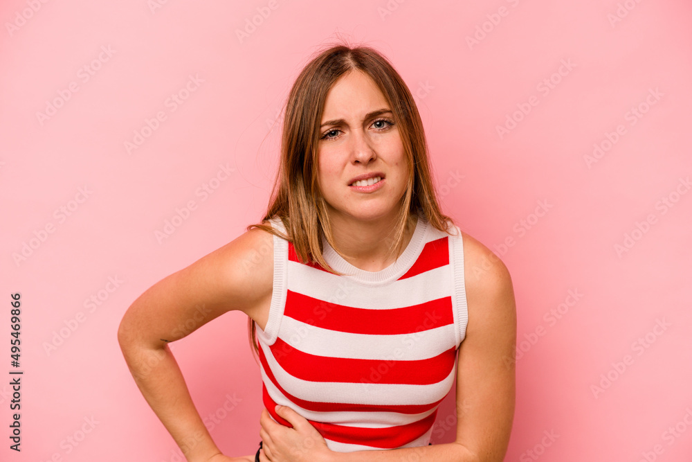 Young caucasian woman isolated on pink background having a liver pain, stomach ache. Young caucasian woman isolated on pink background having a liver pain, stomach ache.
