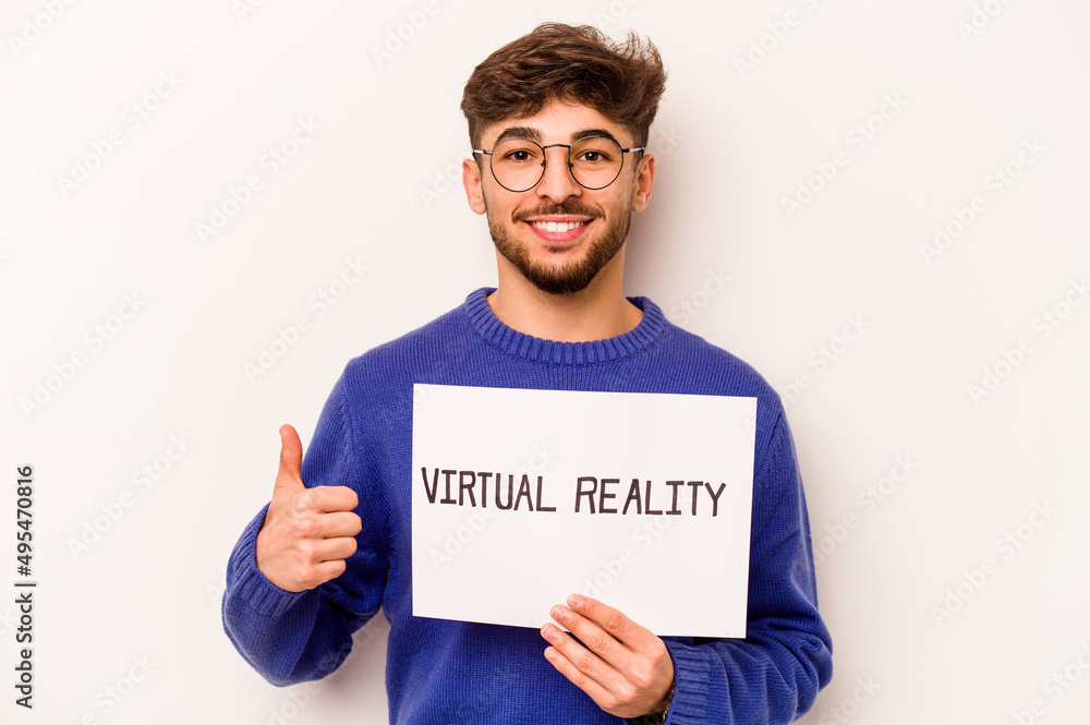 Young hispanic man holding a virtual reality placard isolated on white background smiling and raising thumb up Young hispanic man holding a virtual reality placard isolated on white background smiling and raising thumb up