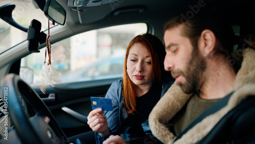 Man and woman couple holding credit card driving car at street