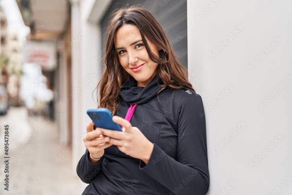 Young hispanic woman wearing sportswear using smartphone at street Young hispanic woman wearing sportswear using smartphone at street