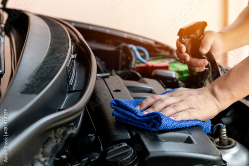 Car clean concept, Hand a man holding microfiber and spray cleaner cleaning engine room of car after car wash for the cleanliness and maintenance of the car