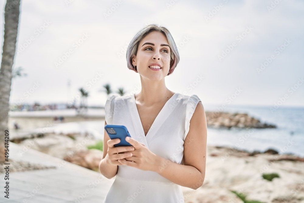Young caucasian girl smiling happy using smartphone at the beach. Young caucasian girl smiling happy using smartphone at the beach.