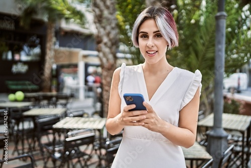 Young caucasian girl smiling happy using smartphone at the city.