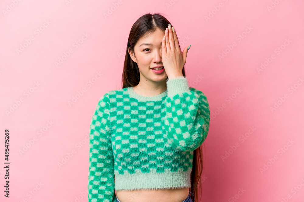 Young Chinese woman isolated on pink background having fun covering half of face with palm. Young Chinese woman isolated on pink background having fun covering half of face with palm.