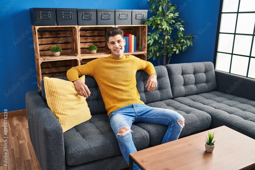 Obraz premium Young hispanic man smiling confident sitting on sofa at home