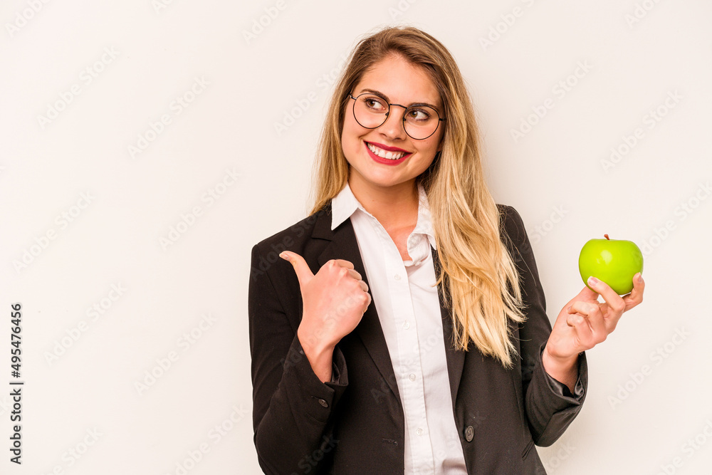 Young business caucasian woman holding an apple isolated on white background points with thumb finger away, laughing and carefree. Young business caucasian woman holding an apple isolated on white background points with thumb finger away, laughing and carefree.