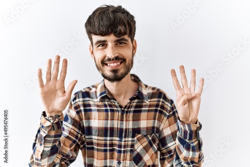 Hispanic man with beard standing over isolated background showing and pointing up with fingers number nine while smiling confident and happy.