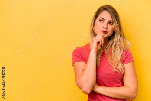 Young caucasian woman isolated on yellow background relaxed thinking about something looking at a copy space.