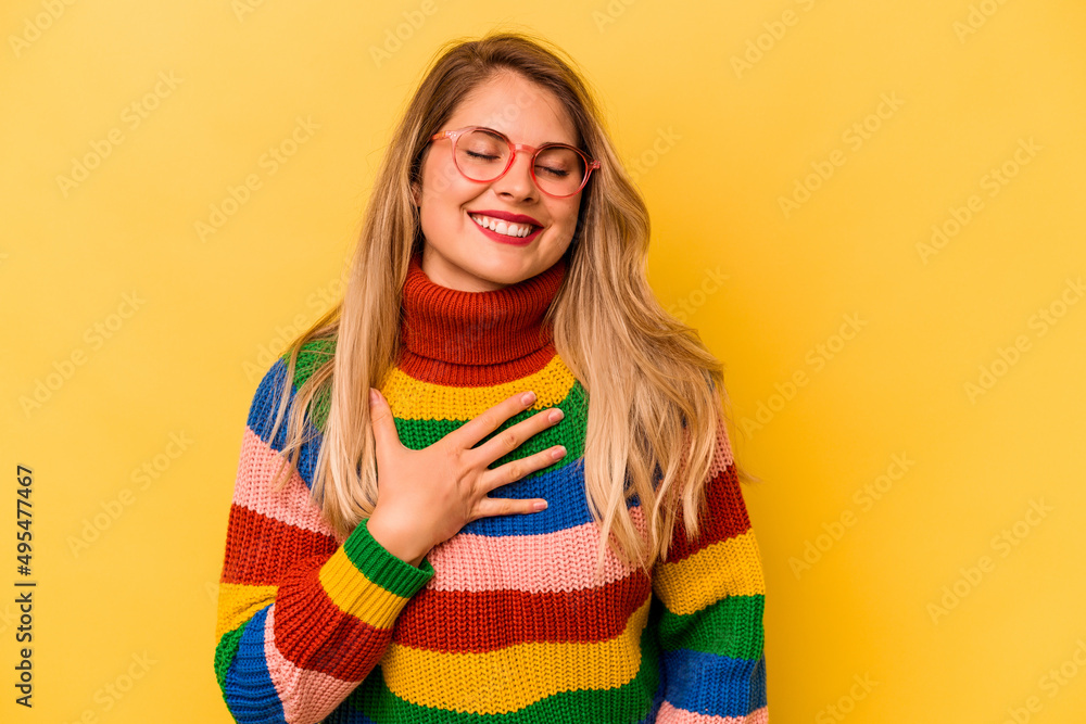 Young caucasian woman isolated on yellow background laughing keeping hands on heart, concept of happiness. Young caucasian woman isolated on yellow background laughing keeping hands on heart, concept of happiness.