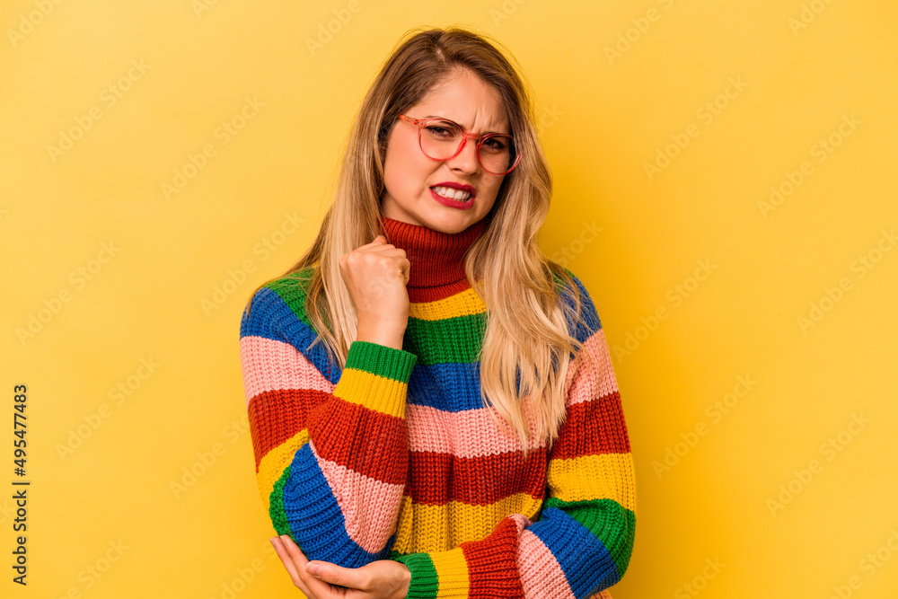 Young caucasian woman isolated on yellow background massaging elbow, suffering after a bad movement. Young caucasian woman isolated on yellow background massaging elbow, suffering after a bad movement.
