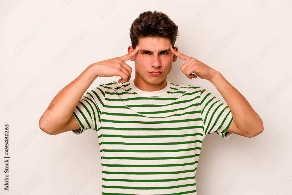 Young caucasian man isolated on white background focused on a task, keeping forefingers pointing head. Young caucasian man isolated on white background focused on a task, keeping forefingers pointing head.