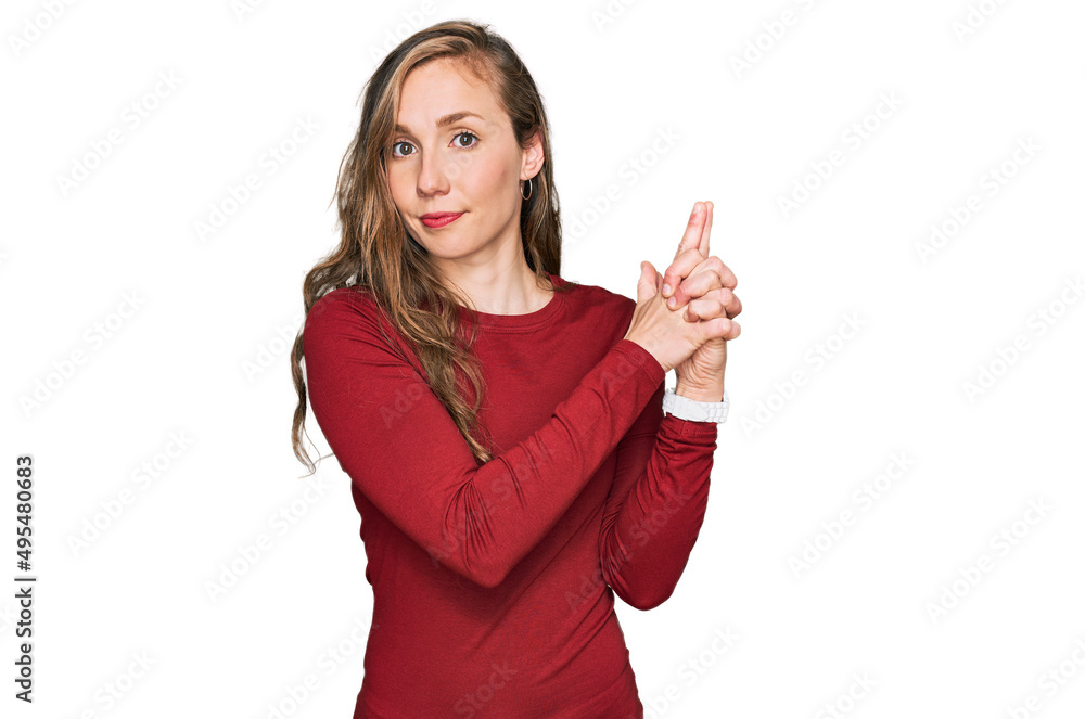 Young blonde woman wearing casual clothes holding symbolic gun with hand gesture, playing killing shooting weapons, angry face Young blonde woman wearing casual clothes holding symbolic gun with hand gesture, playing killing shooting weapons, angry face