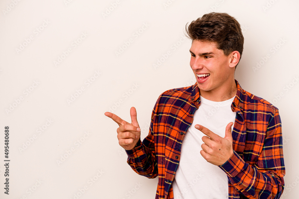 Young caucasian man isolated on white background points with thumb finger away, laughing and carefree. Young caucasian man isolated on white background points with thumb finger away, laughing and carefree.