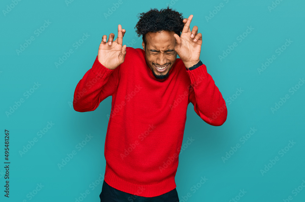 Young african american man with beard wearing casual winter sweater gesturing finger crossed smiling with hope and eyes closed. luck and superstitious concept. Young african american man with beard wearing casual winter sweater gesturing finger crossed smiling with hope and eyes closed. luck and superstitious concept.